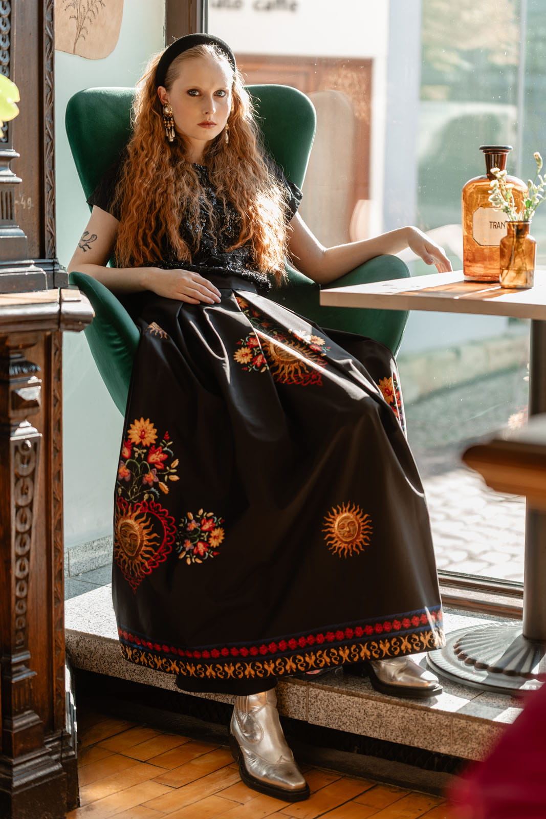 Spódnica Folk – widok z przodu, modelka siedzi; wzory folkowe z motywami serc i słońc.